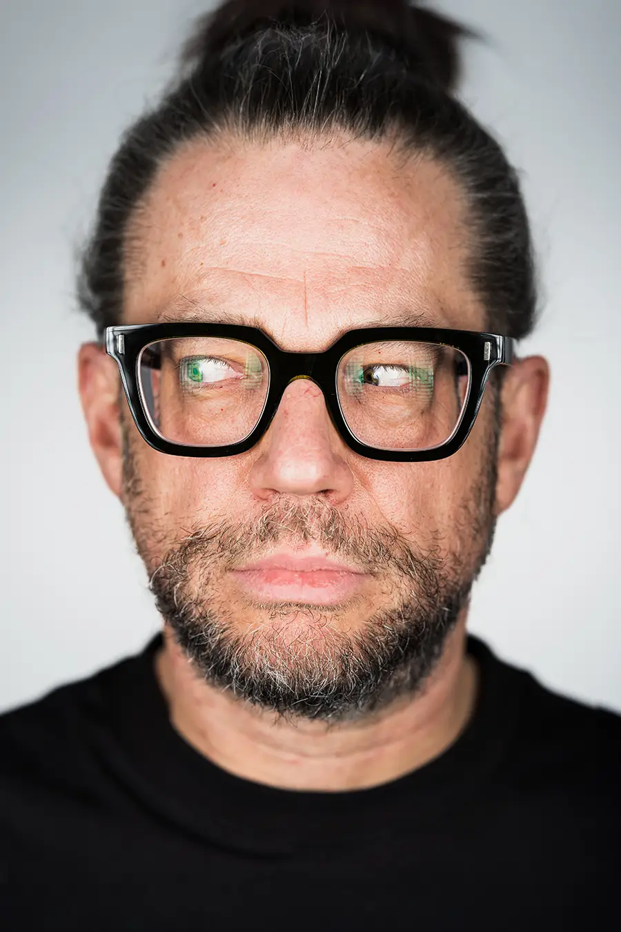 Porträt von Prof. Dr. med. Axel Menzebach M.A. mit schwarzer Brille und nach links blickenden Augen vor hellem Hintergrund